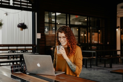 girl drinking an iced coffee at a cafe on her macbook.