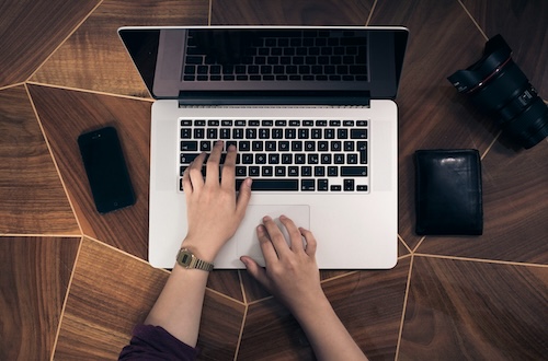 hands typing on macbook keyboard